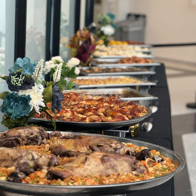 A buffet table laden with large platters of middle-eastern roasted meats and rice dishes.