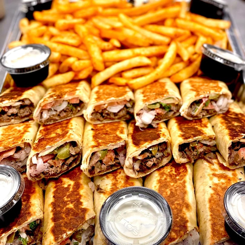 A tray of SK Shawarma wraps and golden french fries with dipping sauces.
